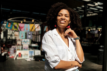 Smiling curly woman in flea market indoors.