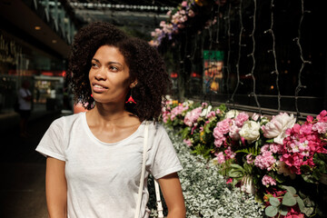 Curly black woman walking in a flower market.