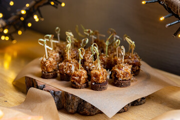 Canapes with tuna and tuna shavings on a rye bread all together with skewers on a wooden board