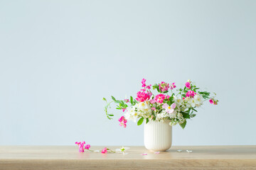 summer flowers in ceramic cup on light background