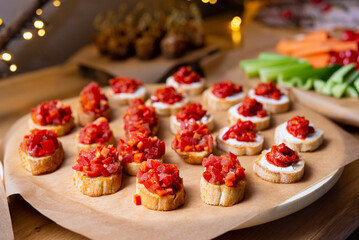 Appetizer crostini with tomatoes, diced red bell peppers and cream cheese spread. Catering buffet food.