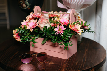 Bouquet of flowers in pink wooden box basket on a wooden round table