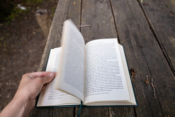 Fototapeta premium Close up photo of a caucasian woman reading a book on a table in the forest.