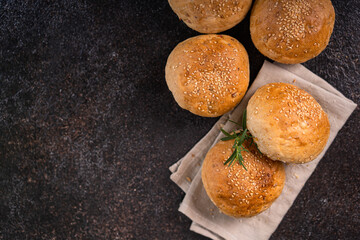 Homemade whole grain brown buns with sesame seeds on rustic background. Healthy artisan bread.