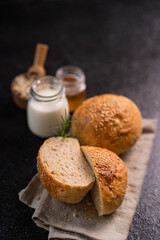Homemade whole grain brown buns with sesame seeds on rustic background. Healthy artisan bread.