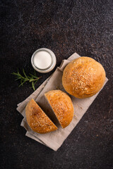 Homemade whole grain brown buns with sesame seeds on rustic background. Healthy artisan bread.