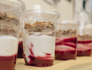 portions de yogourt et confiture de fraise avec des flocons d'avoine dans des pots en plastiques  avec couvercle sur une table