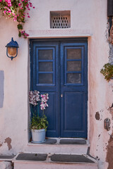 Fototapeta na wymiar Wooden Blue Door Entrance to a Traditional House - Oia Village, Santorini Island, Greece - Travel Destination, Summer, Sunset