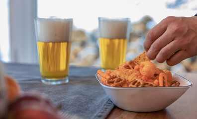 vue sur une table avec un bol plein de snack avec deux verre rempli de bière avec mousse