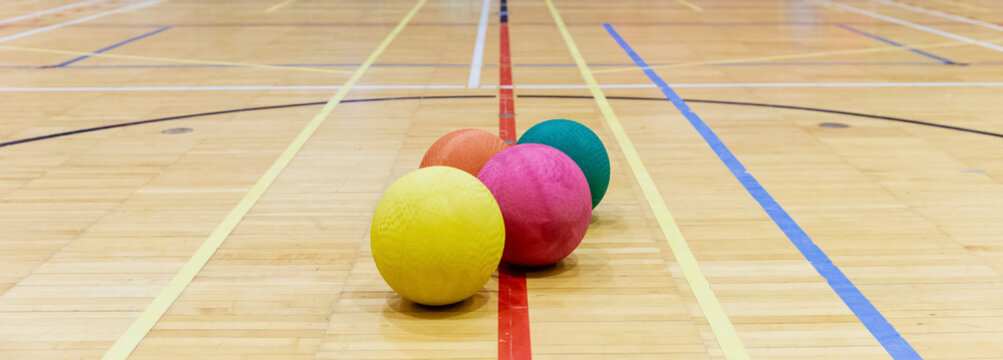groupe de ballons color&eacute;s en caoutchouc sur le sol en bois d'un gymnase int&eacute;rieur