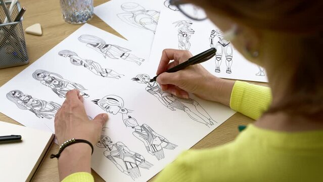 An artist draws characters for computer games. Illustrator drawing sketches on paper. Animation design studio. Animator designer. 