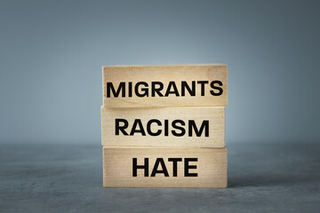 The problem of racism and hate migrants, Written on wooden blocks Migrants Racism Hate, Sad gray background, copy space, Concept related to immigrants and hate language