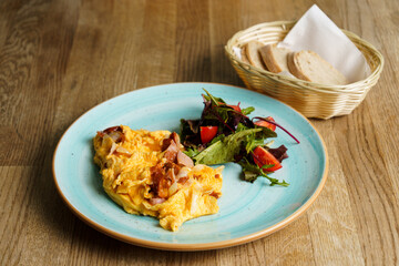 Scrambled eggs with ham, tomato, vegetables and rustic bread