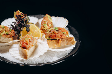 Cold fish appetizer on a black plate