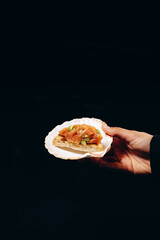 Salmon and avocado tartar in shell on the black background