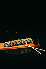 Salmon Dragon sushi on a wooden board with Chinese chopsticks