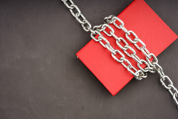 a book wrapped in a chain on a gray background, a shiny chain and a red book
