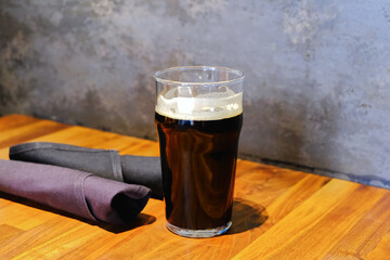 Dark beer glass on restaurant table food and drink background texture close up photo with copy space. Biergarten, beer garden, brewery, pub, bar or taproom. 