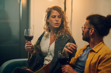 Beautiful young girl talking to her boyfriend while holding a glass of wine.