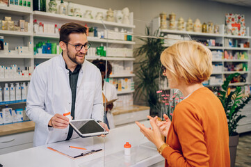Male pharmacist giving prescription medications to a senior patient in pharmacy