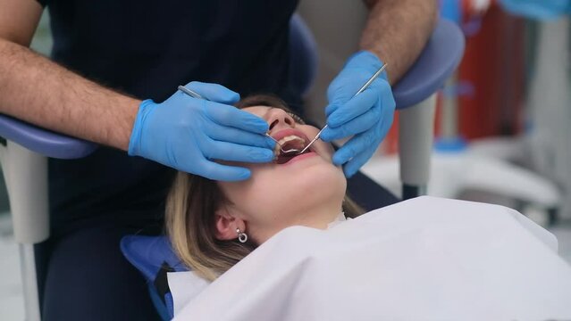 Modern dentistry clinic with innovative equipment and treatment dentist checking teeth of young woman process of professional cavity checkup of female patient