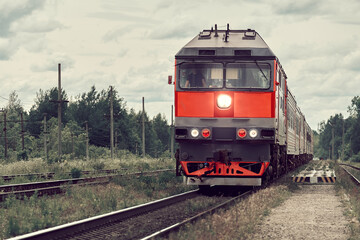 Soviet passenger train rides on rails through the forest. Russian diesel locomotive pulling passenger cars.