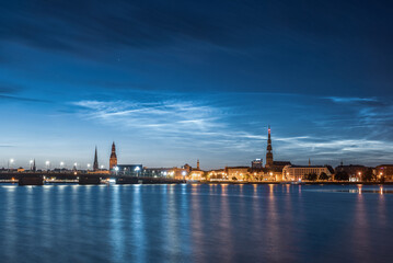 Fototapeta premium Noctilucent clouds over the Daugava river and view to Old Riga Town and stone bridge on July night. Long exposure photography.