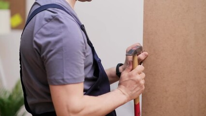 Furniture manufacturing and shipping firm worker in coveralls hammering nail making wooden wardrobe for bedroom interior commercial carpentry business man working with instruments