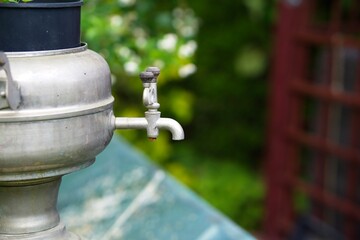 An old metal jug with a faucet as a garden decoration       