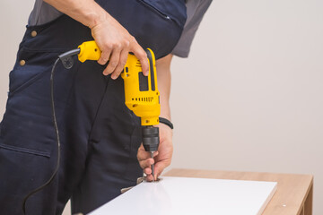 Furniture assembly and fixing carpenter electric screwdriver office rack made of quality wooden materials specialist preparing new furniture for interior design