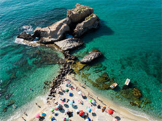 Fototapeta premium Italy, July 2023: aerial view from drone of caribbean sea and beach with tourists and umbrellas at Baia di Riaci near Tropea in Calabria