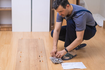 Modern furniture assembling service employee in coveralls putting smooth wooden planks to rack designed for office interior carpentry industry and business