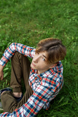 Portrait of serious teenager sitting on grass in park. Gen Z. Top view. Identity development.