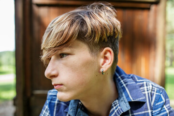 Portrait of serious teenager sitting on grass in park. Gen Z. Unhappy and stress.