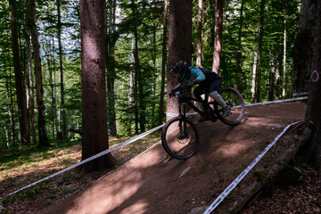 Professional cyclist is riding the mountain bike.Extreme sport and enduro biking concept.Man in full face helmet enjoying downhill mountain biking in bike park.