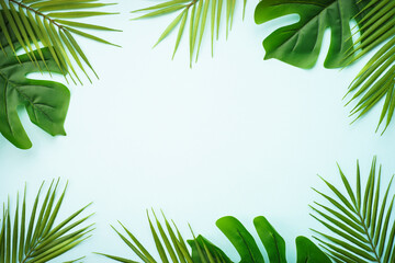 Summer flat lay background. Tropical leaves, palm leaves and monstera on blue background.