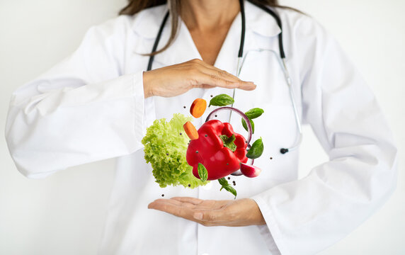Adult european woman doctor nutritionist in white coat hold organic fruits , vegetables in hands