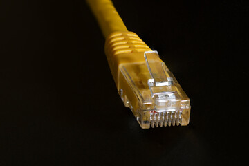 Macro photo of a yellow 8 pin ethernet plug on black background