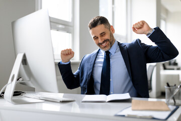 Fototapeta premium Smiling middle aged businessman stretching after working day in office, european man sitting at desk with computer