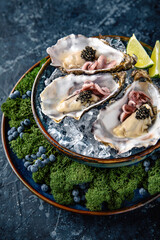 Fresh oysters with black sturgeon caviar and octopuses in a luxurious serving in blue ceramic plates with ice, lime. Michelin restaurant.