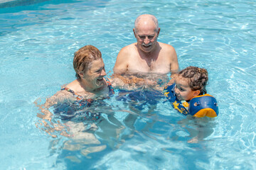 Elderly people playing in the water with small child