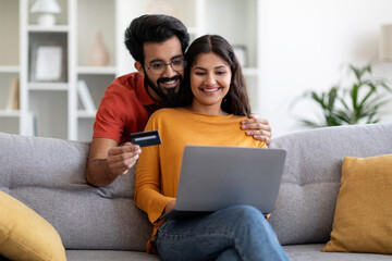 Indian Couple Making Online Shopping With Laptop And Credit Card At Home