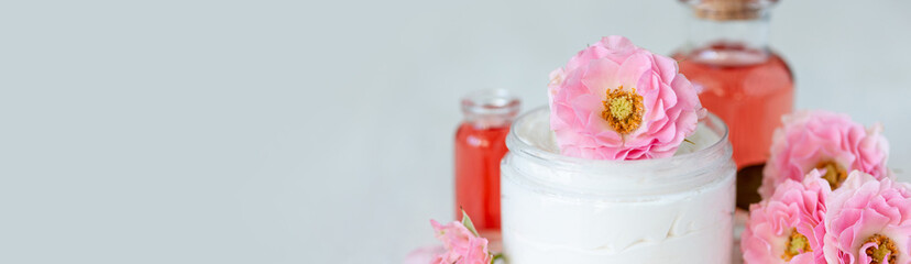 Concept of perfume with pure natural organic rose ingredient, essential oils. Glass bottles with flower herbal extract and elixir. Perfumery cosmetic toilet water fragrance, banner copy space for text