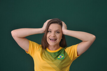 jovem mulher brasileira sorridente e feliz torcedora pela sele&ccedil;&atilde;o do brasil, copa do mundo de futebol. cores verde e amerelo amor a bandeira do brasil 