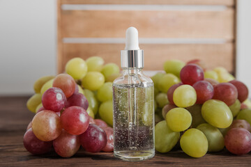 Serum on wooden trending podium and grapes in cut. Skincare, healthcare concept from grape seed oil. Top view.