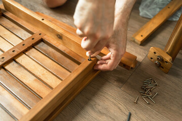A man makes wooden A master with tools repairs furniture. Furniture repair. Dad collects furniture at home. Restoration of home furniture