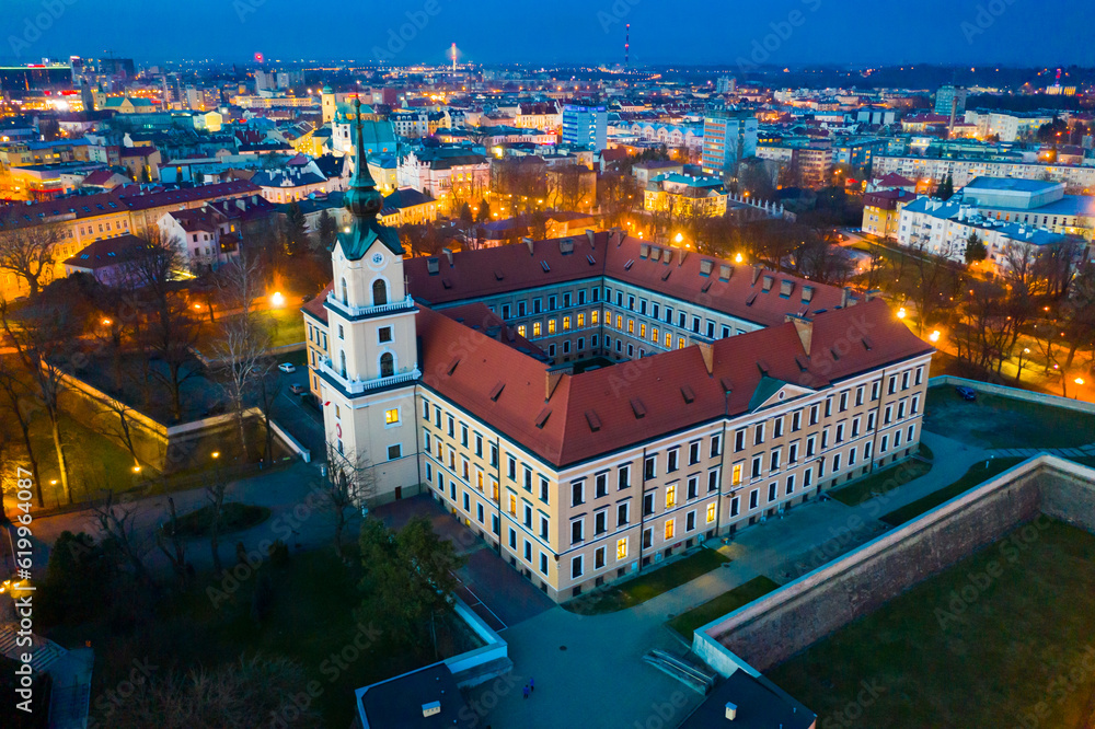 Wall mural Aerial view of Renaissance building of Rzeszow castle on background of lighted cityscape at twilight, Poland