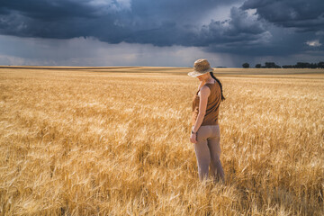 Rear view of woman looking while standing in crop against cloudy sky with storm and rain