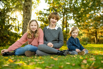 Two big sisters and their toddler brother having fun outdoors. Two young girls with a toddler boy on autumn day. Children with large age gap. Big age difference between siblings.