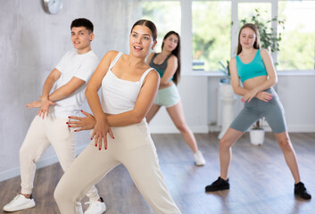 Obraz premium Smiling females and males doing dance workout during group classes in fitness center